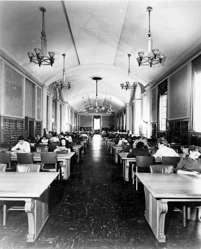 A black and white vintage photo of students reading in a hall.