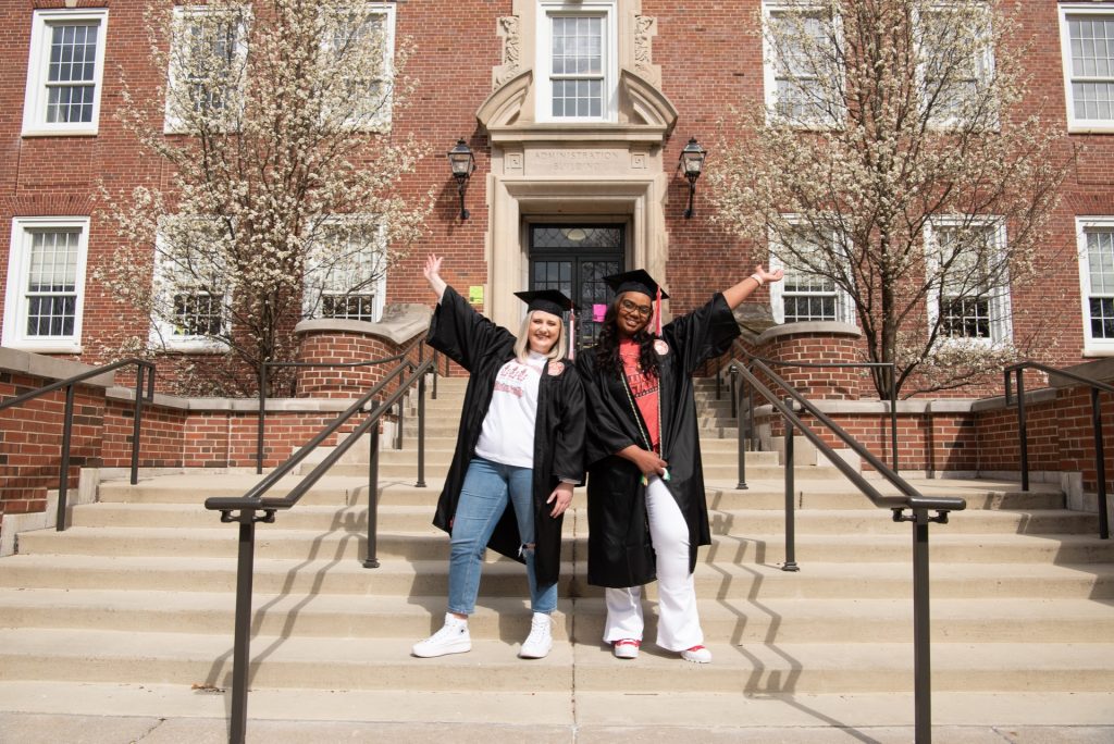 Two graduates posing in front of a building
