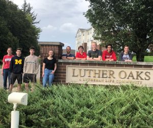 Students pose by the sign for Luther Oaks