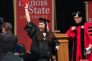 student at Commencement waving diploma