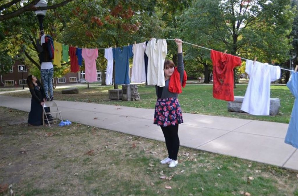 Illinois State student and ISU F.L.A.M.E. member Kristina Harlow helps hoist The Clothesline.
