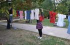 Illinois State student and ISU F.L.A.M.E. member Kristina Harlow helps hoist The Clothesline.