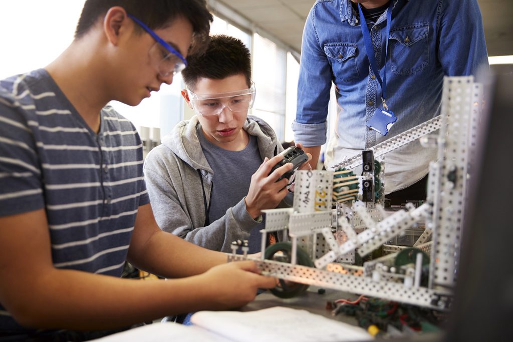 Teacher With Students building machine In science robotics class