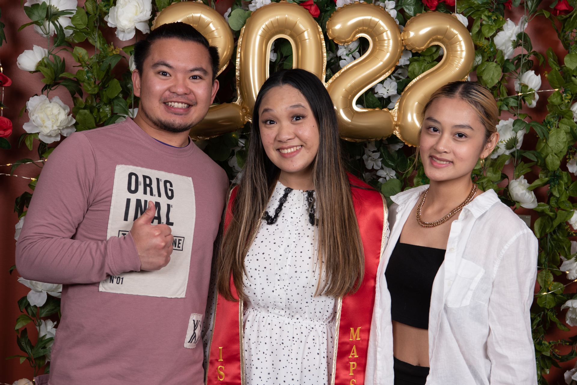 A graduate stands in the middle while two others pose with side by side.