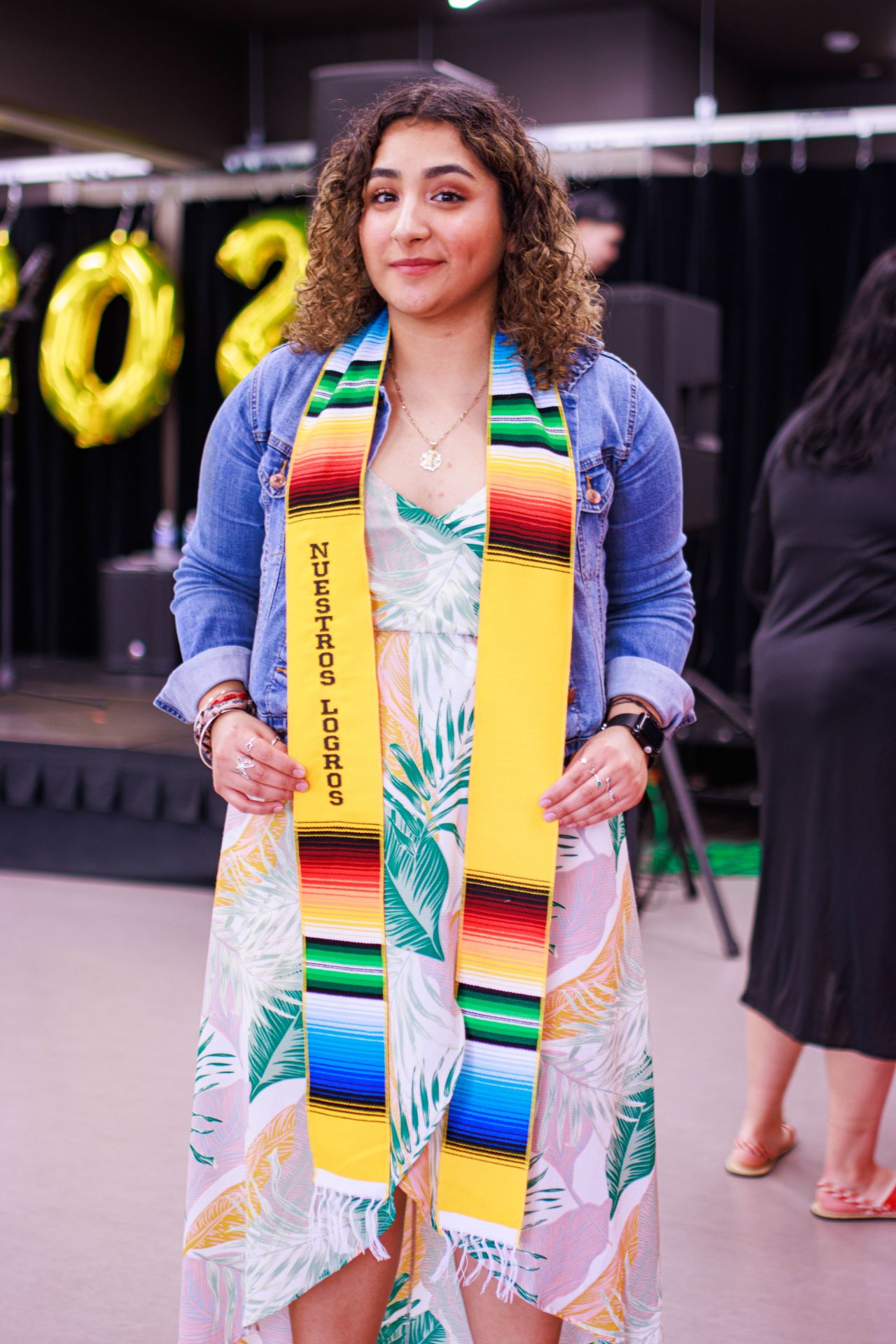 A graduate poses with their graduation sash.