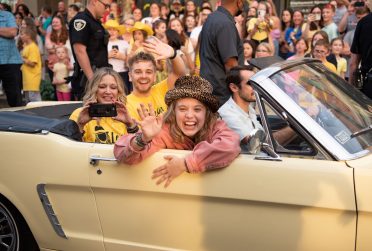 four people riding in a yellow convertible