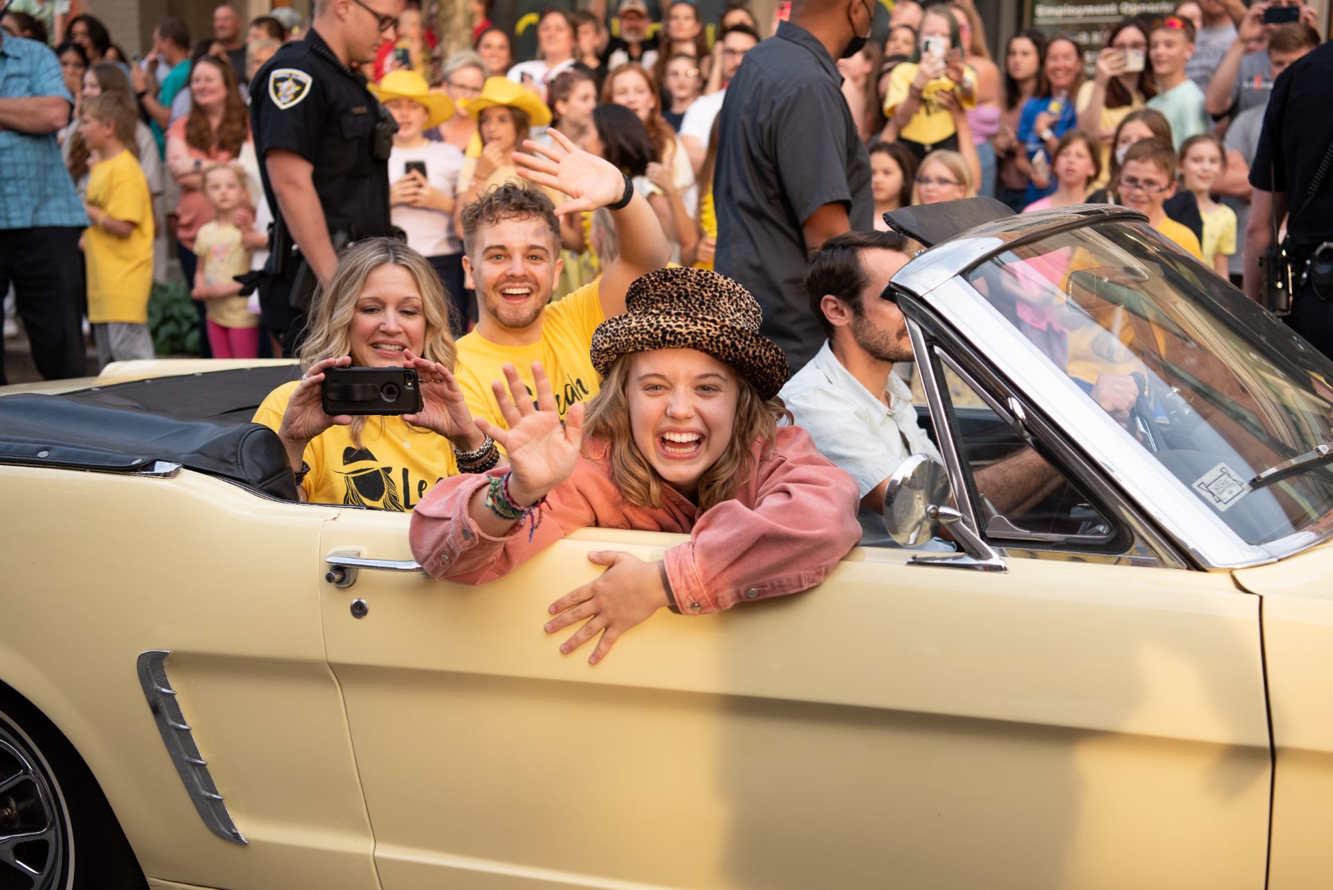 four people riding in a yellow convertible
