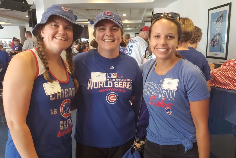 three women smiling and wearing Cubs shirts