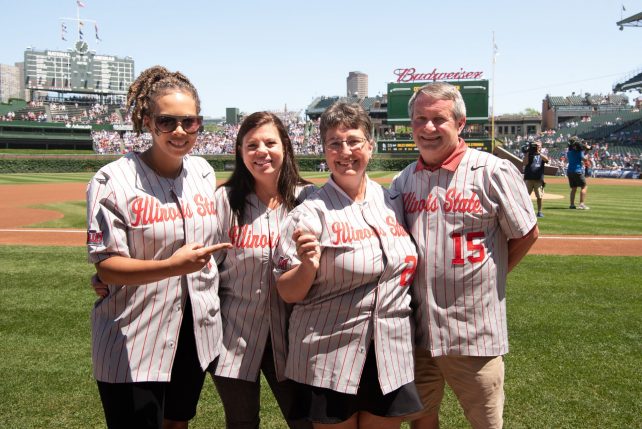 Four people wearing Illinois State baseball jerseys standing together on Wrigley Field