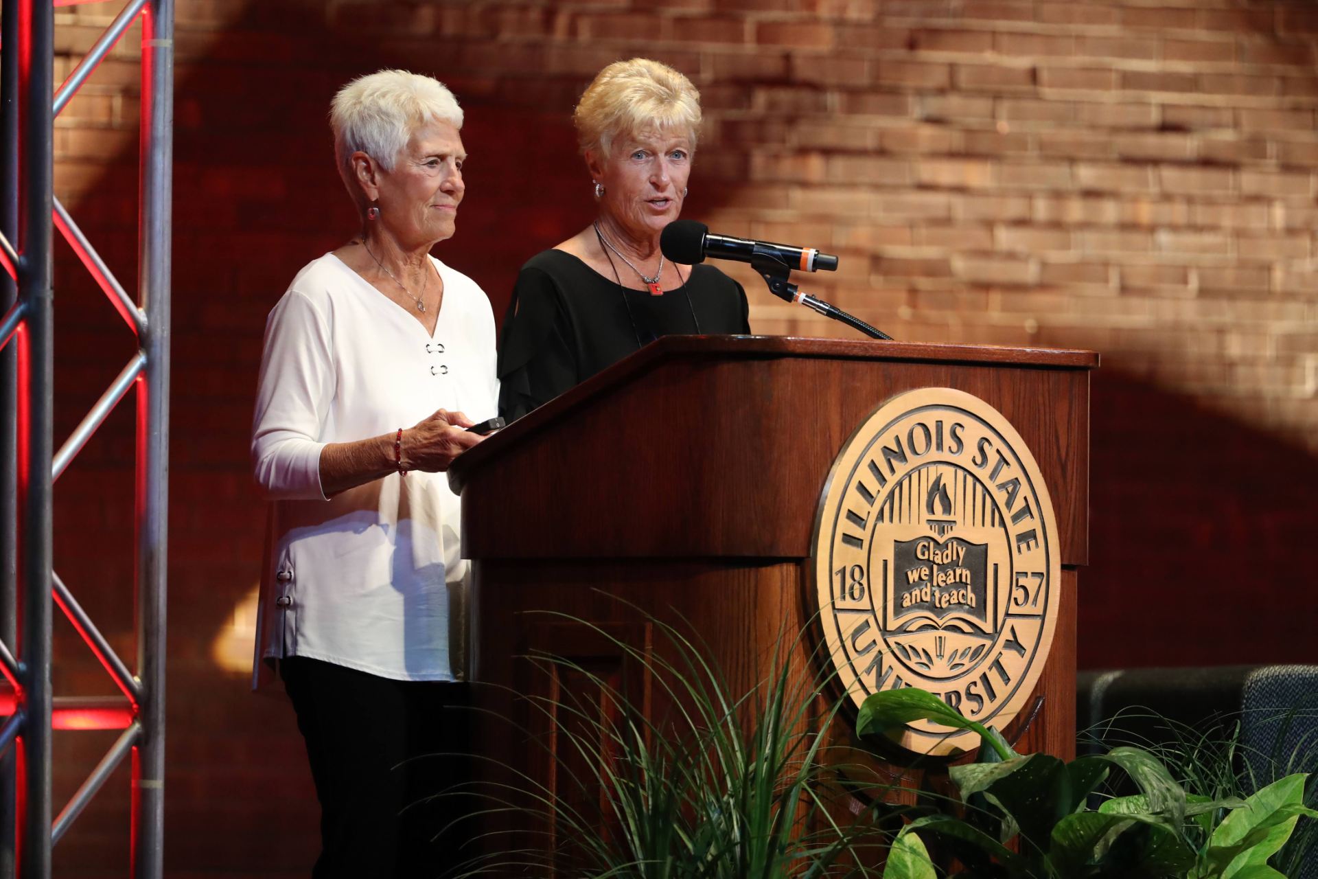 Two women talking on a podium.