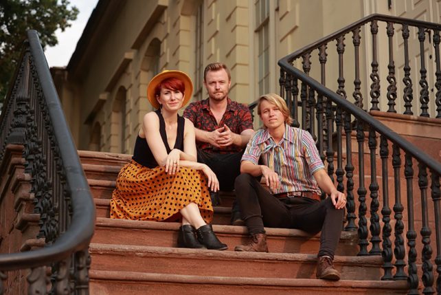 Promo image for House of Hamill depicting the band members sitting on a staircase outside of a building.