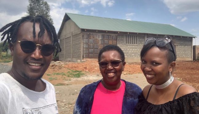 Melon and her mother and brother standing in front of a stone building in Kenya.
