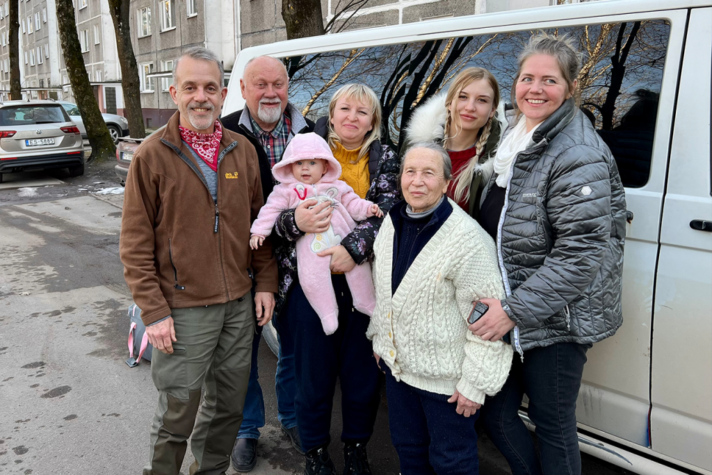 A group of people standing in front of a van smiling