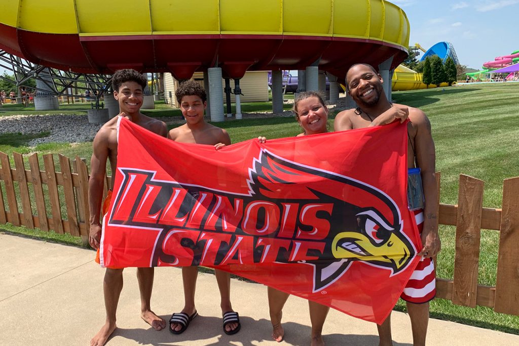 family of four holding up Redbird flag