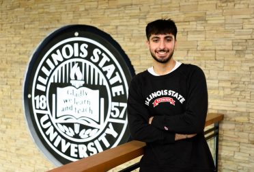 student posed in front of ISU seal