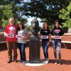 Paul Burton ’73 with daughters Elisabeth Drebes ’90 and Lynn Bartimus ’91 and granddaughter Natalie Bartimus ’22 with Reggie head statue