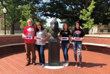 Paul Burton ’73 with daughters Elisabeth Drebes ’90 and Lynn Bartimus ’91 and granddaughter Natalie Bartimus ’22 with Reggie head statue