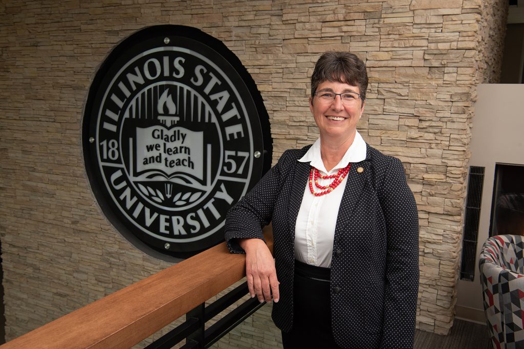 woman standing next to seal with words that say Illinois State University