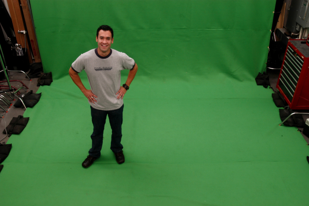Man standing and smiling in front of a green screen