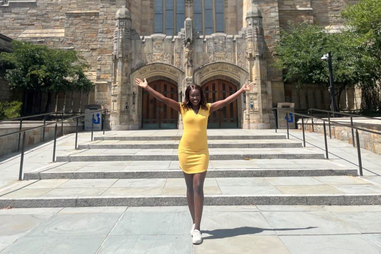 student posing in front of Yale library