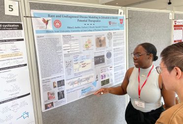 student points at research poster