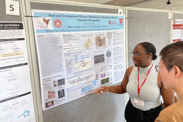 student points at research poster