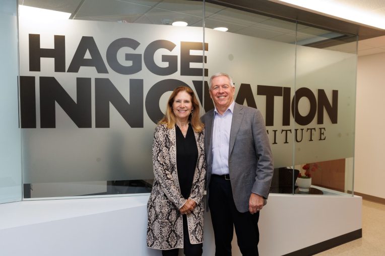 Sharon and Stephen Hagge standing together in front of glass with "Hagge Innovation Institute" written on glass behind them