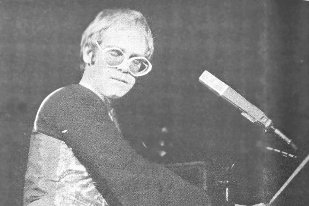 Black and white photo of Elton John playing the piano