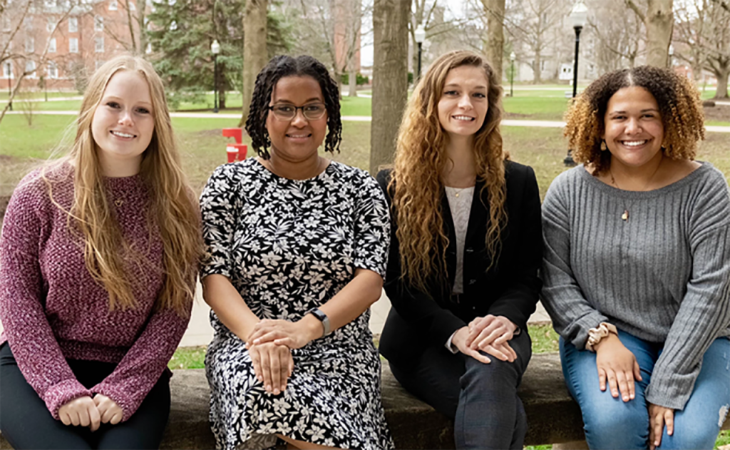 WGLT Scholarship winners Mary Kloser ’22, Samantha Hill, and Jordan Mead, and WCBU Scholarship winner Olivia Streeter, all sitting on a bench in the Quad