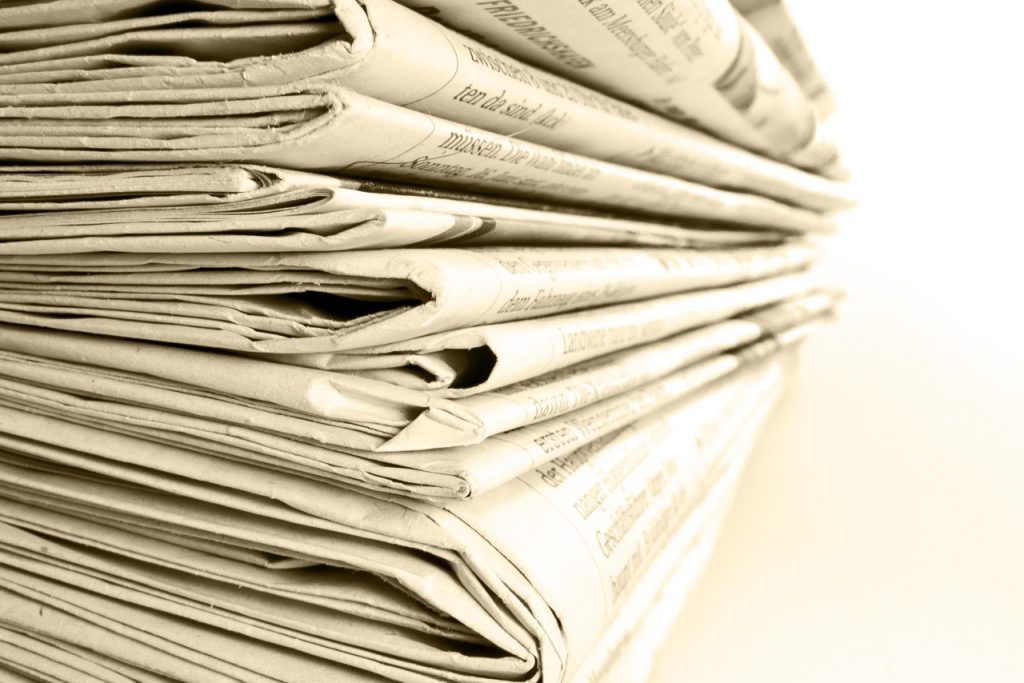 A close-up of a stack of newspapers on white background