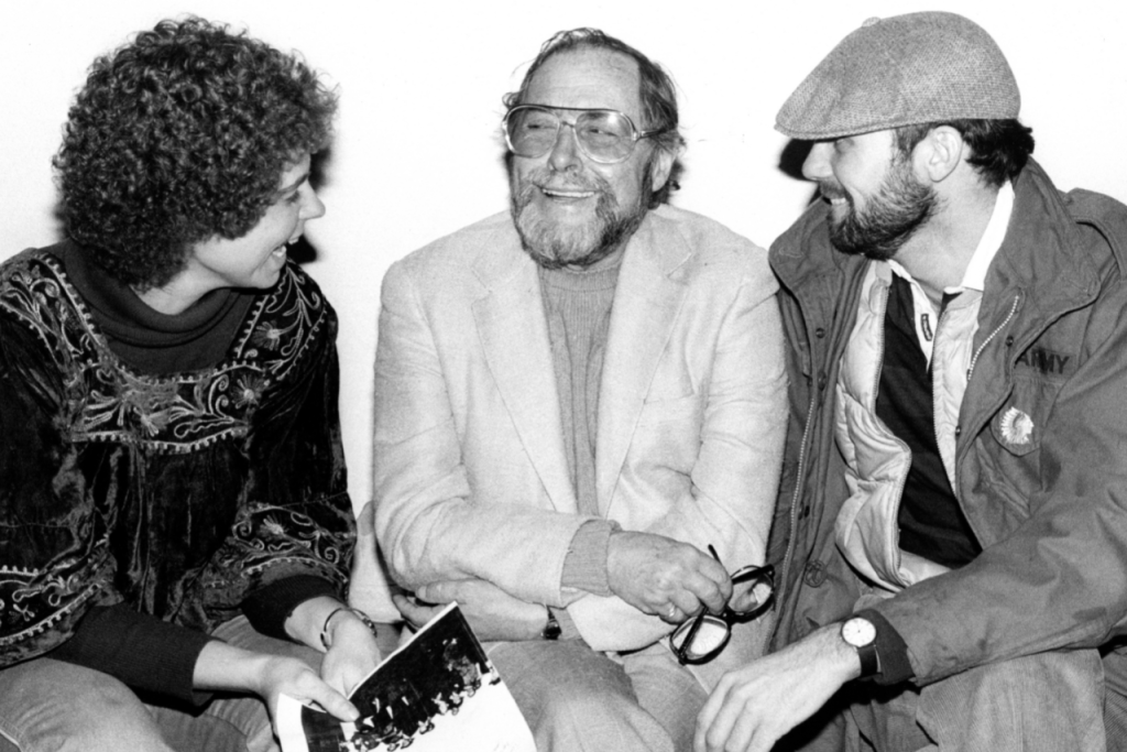 A woman and two men smiling and talking