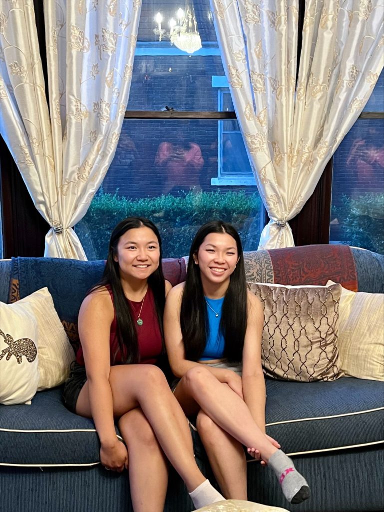 The two sisters sit together on a couch