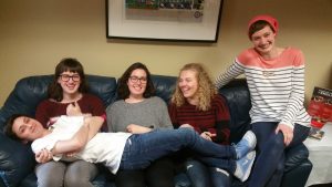 Five people laughing and lounging on a couch.