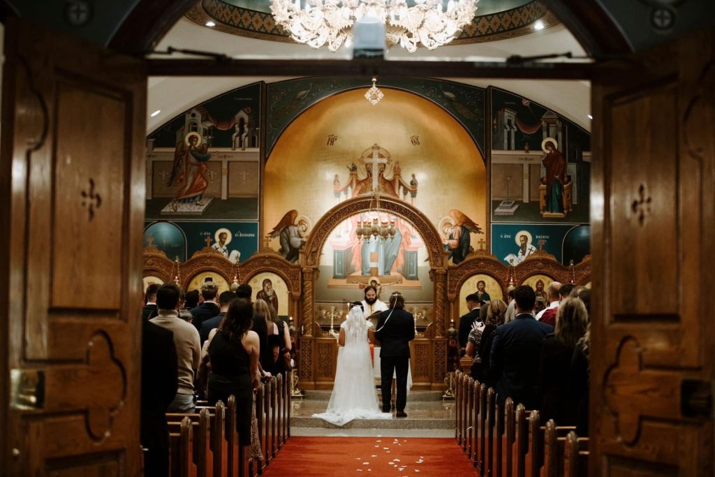 Mia Leyba ’17 and Jordan Ross ’17 wearing wedding attire standing in a church