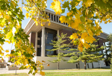 Milner Library from the outside as pictured behind some leaves