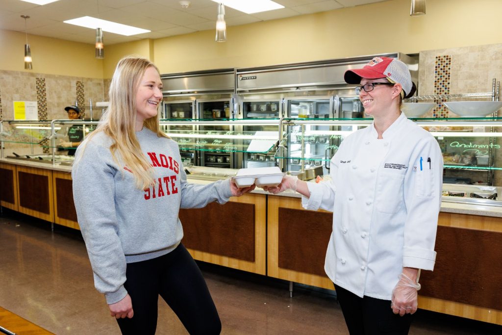 Student Gabby Stopka is handed a meal to-go by chef Ursula Ganci