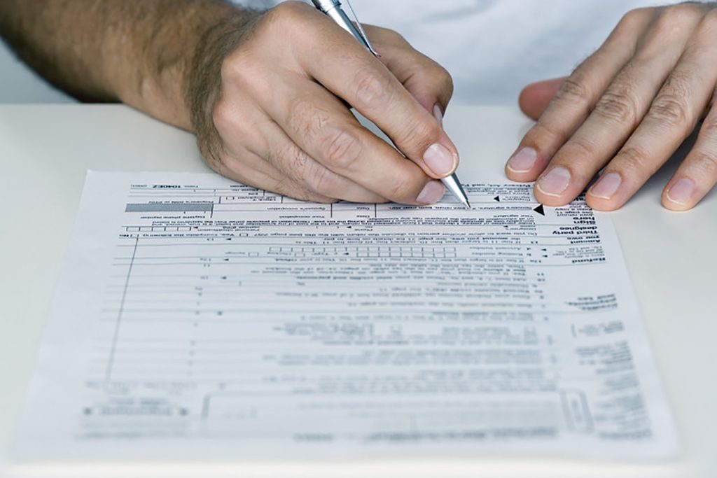 Man Filling out Tax Form --- Image by © Royalty-Free/Corbis