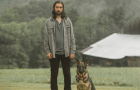 Noah Kahan standing in a field next to a dog