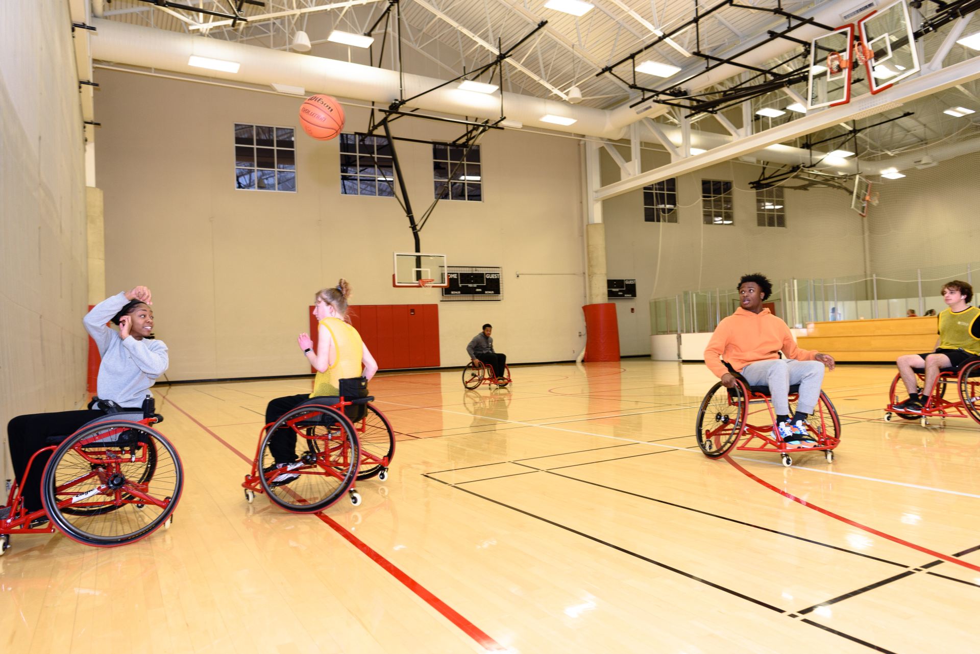 One student in a wheelchair passes a basketball to their teammate