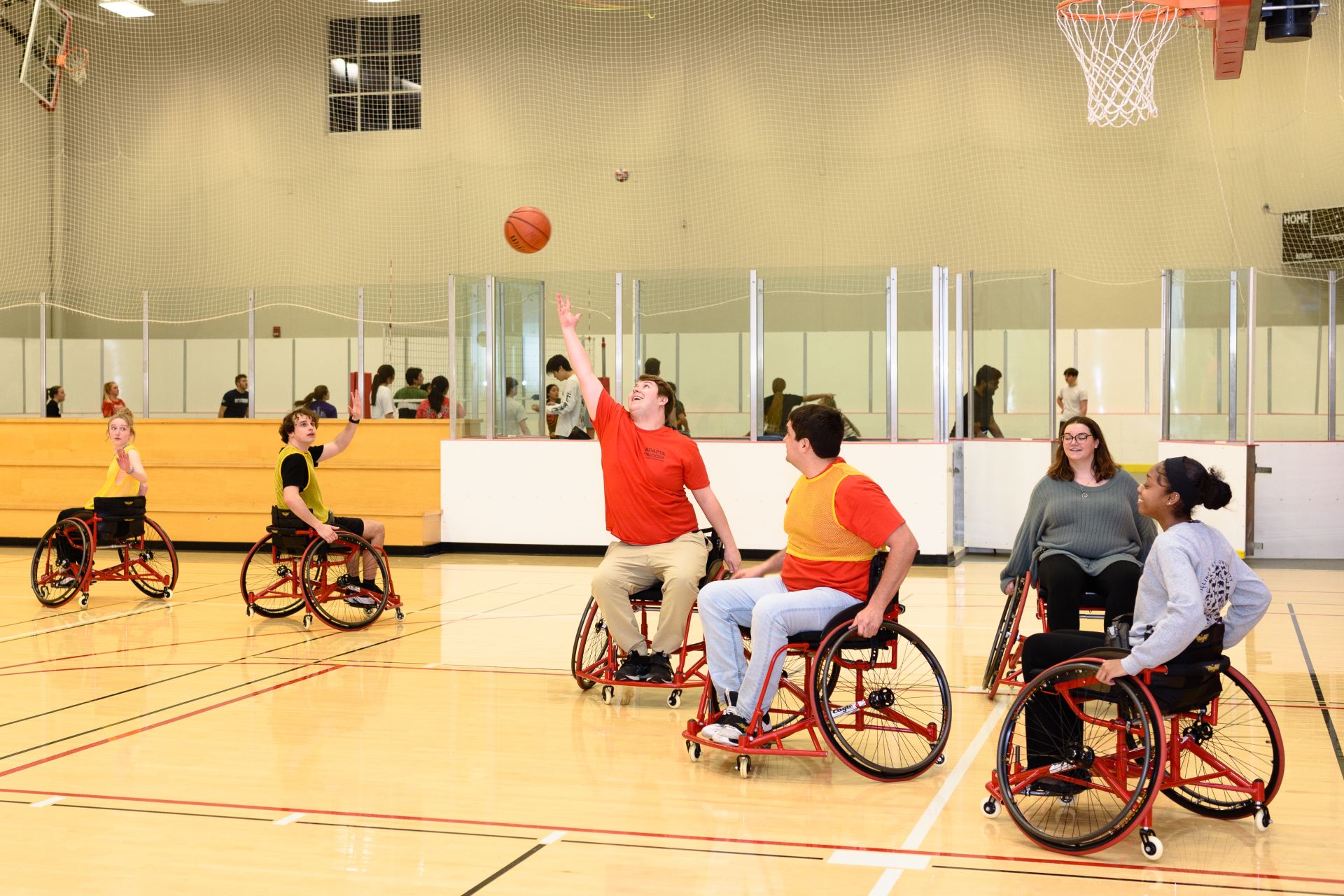 A student in a wheelchair reaches up to catch a basketball