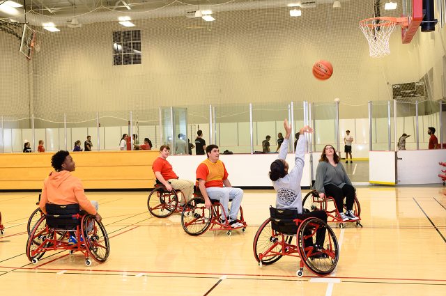 A student shoots a basket while playing wheelchair basketball