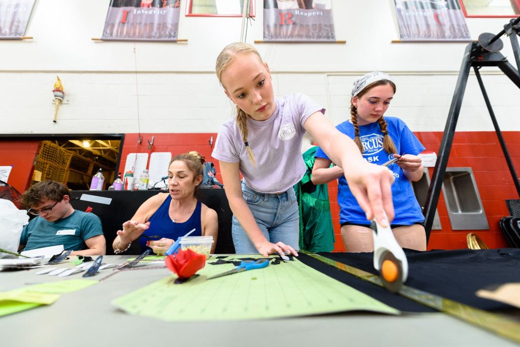 A student cuts fabric to create a Gamma Phi Circus Costume.