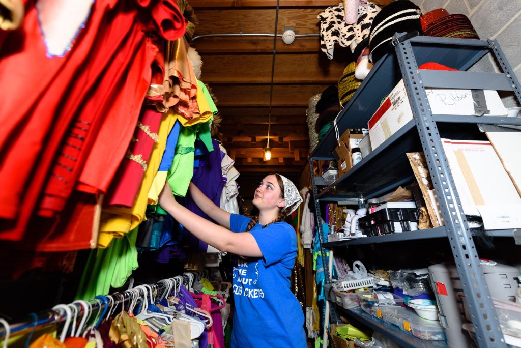 A student looks at hanging costumes in storage.