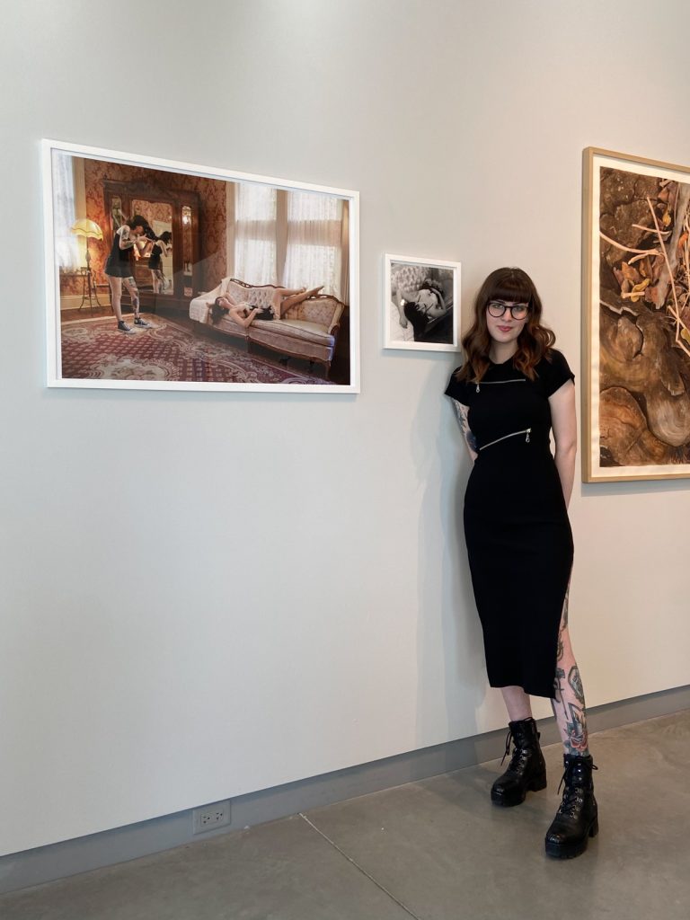 Sarah poses with her series "Third Person" at University Galleries Student Annual Exhibition in 2023.