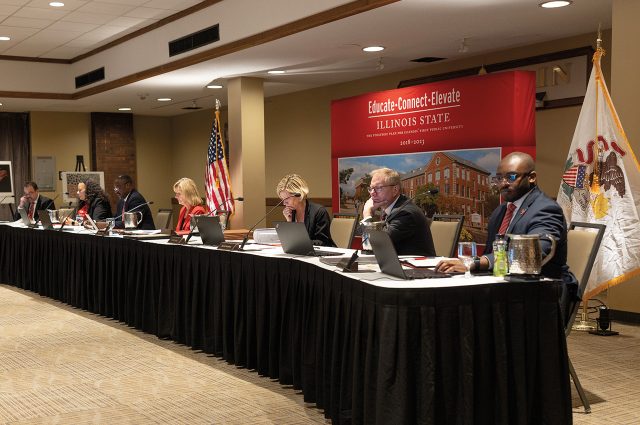 Members of the board of trustees sitting at a long table at a board meeting