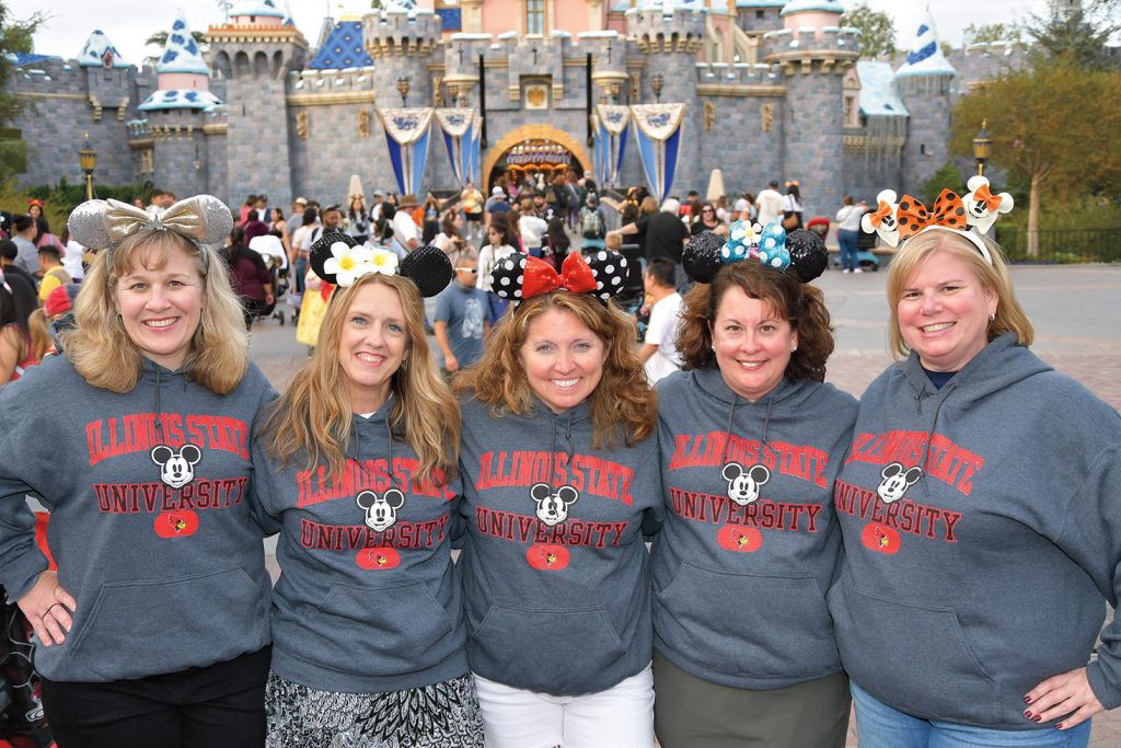 Five alumni posing at Disney World wearing the same Illinois State and Disney branded sweatshirts