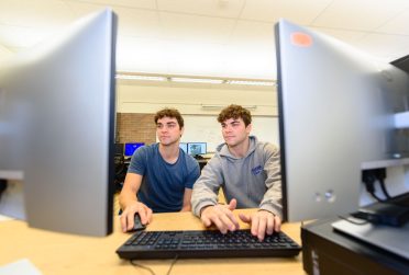 students who are identical twin brothers look at a computer screen