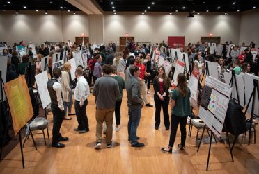 Students present posters at research symposium.