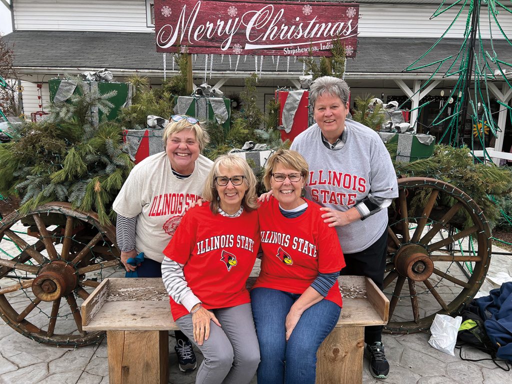 Four alumni posing at a Christmas-themed outdoor shopping location