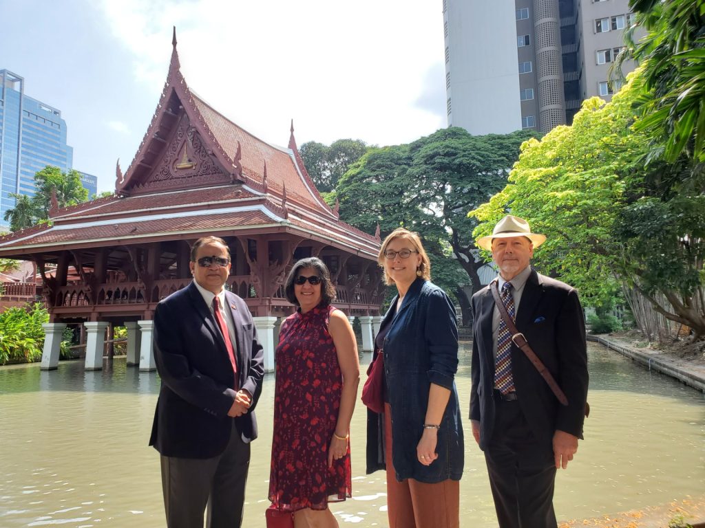 two men and two women standing in front of a Thai temple
